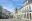 Wide cobblestone street lined with houses with large arched windows painted in pale pink, pistachio and pale blue