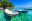 Two wooden boats moored in crystal clear jade green water with wooded island beyond