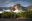 Waterfall thundering over high flat-topped mountain into clouds floating across forest canopy under a blue sky dotted with cumulus clouds